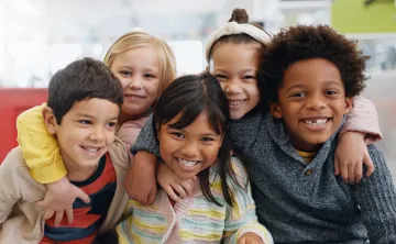 A diverse group of young children sitting together and smiling at the camera.