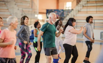 A diverse group of people dancing together in a gym.