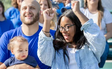 A mother and father at a sporting event with their young child.