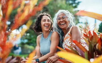 Two women sitting outdoors laughing together.