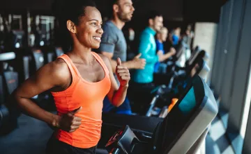 A woman running on a treadmill at the gym.