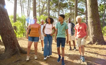 A diverse group of people ranging from teenager to seniors walking together in the forest.