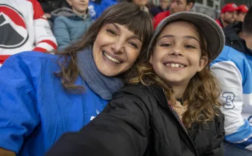 A mother and daughter taking a selfie together at a hockey game. They are smiling into the camera.