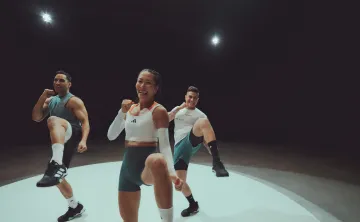 A group of three people in fitness clothing in a LES MILLS BODYCOMBAT class.