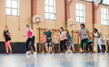 A diverse group of people dancing together in a gym.