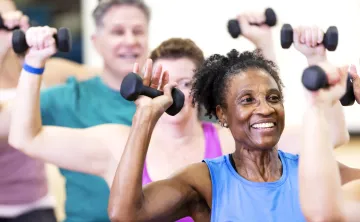 A senior woman in a group exercise class. The class is using handweights.