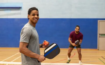 Two men in gym playing pickleball
