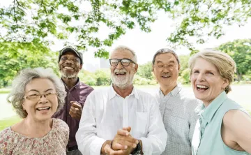 A group of seniors standing outdoors laughing together.