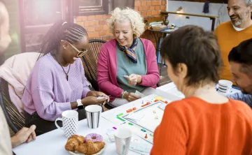 A group of adults playing a board game together. They are laughing.
