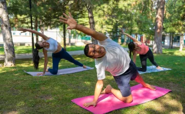 A man in a group exercise class doing yoga outdoors.