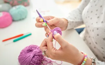 A close-up view of a woman's hands as she is crocheting.