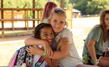 two girls embracing each other excitedly at camp 