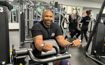 Gentleman smiling at the camera while on weight equipment